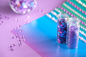 All kinds of glitter products on pink sparkling background. Close-up on vials, bottles with various...