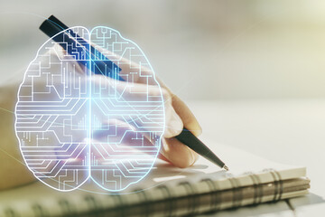 Creative artificial Intelligence concept with human brain hologram and woman hand writing in notebook on background. Multiexposure
