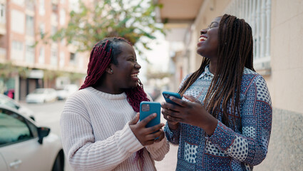 Two african american friends smiling confident using smartphone at street