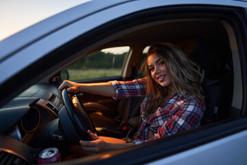 Beautiful woman in the car at sunset