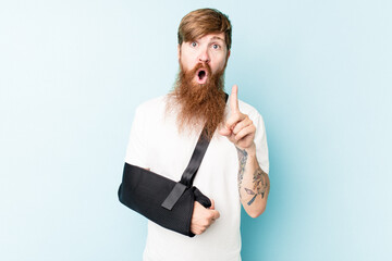 Young caucasian man with broke hand isolated on blue background having some great idea, concept of...