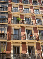 Obraz premium Typical windows and balconies in the Spanish city of Madrid under the hot setting sun.