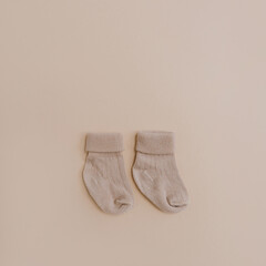 Pair of cozy hygge pastel colourful newborn baby socks on neutral beige background. Aesthetic minimalist baby fashion collage. Happy maternity concept