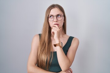 Young caucasian woman standing over white background thinking worried about a question, concerned and nervous with hand on chin