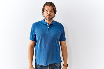 Handsome middle age man standing together over isolated background puffing cheeks with funny face....