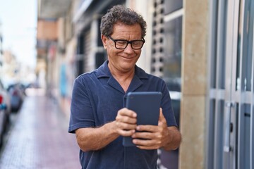 Middle age man smiling confident using touchpad at street