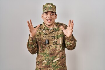 Young arab man wearing camouflage army uniform celebrating crazy and amazed for success with arms raised and open eyes screaming excited. winner concept