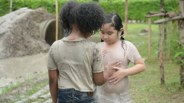 Children washing the mud After having fun playing mud slides in the community fields. with parents watching from a distance