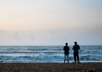 Two friends standing on the beach of the Bay of Bengal and relaxing