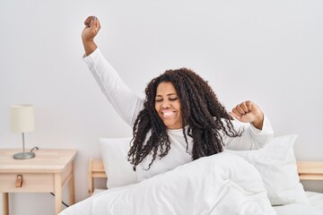 African american woman waking up stretching arms at bedroom