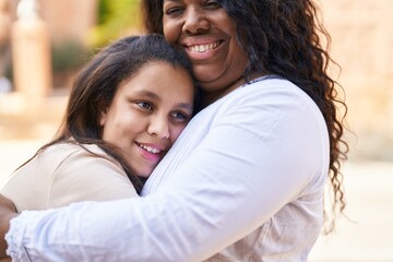 Fototapeta premium Mother and daughter smiling confident hugging each other at street