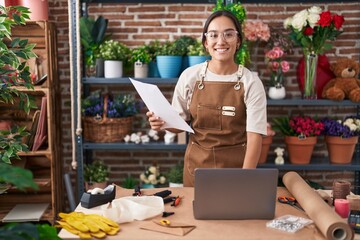 Young beautiful hispanic woman florist using laptop reading document at florist