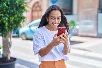 Young beautiful hispanic woman smiling confident using smartphone at street