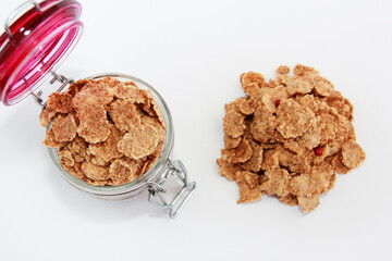 dry wheat diet muesli in a transparent glass jar on a white background