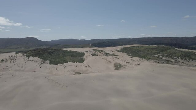 Aerial view of the sand dunes in Llani, Chile with patches of green on it and the mountains in the background