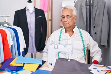 Middle age man with grey hair dressmaker using sewing machine skeptic and nervous, frowning upset because of problem. negative person.