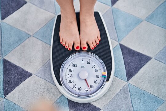 Young Hispanic Woman Using Weighing Machine At Home