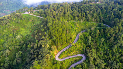 Aerial view of a hilltop road with beautiful green forests in Thailand. Aerial capture with drone.