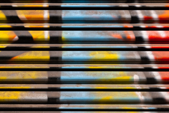 Colorful structures made by street artists. Macro close up of details of graffiti image in yellow, red and blue on a metal roller shutter in Naples Italy with bright side light. Abstract background.