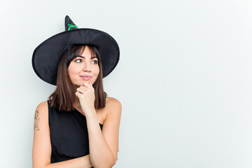 Young caucasian woman dressed as a witch isolated on white background looking sideways with doubtful and skeptical expression.