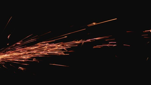 Sparks created by angle grinder flying on black background. Industrial production process details, close-up