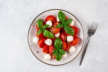 Italian caprese salad with sliced tomatoes, mozzarella, basil, olive oil on a dark background. Top view. Italian food. Healthy salad. Summer food