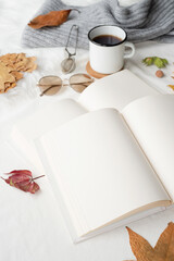 white blank book with autumn leaves and cup of hot tea on old table , mockup design