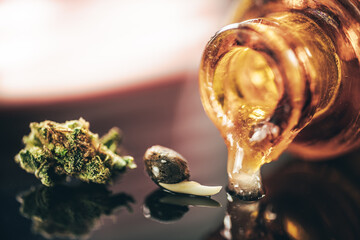 Flowers of Cannabis and oil in small apothecary bootle.