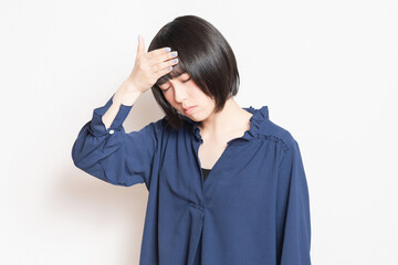 頭痛で痛む頭に手を当てている若い女性