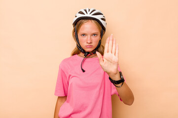 Little caucasian girl wearing a bike helmet isolated on beige background standing with outstretched hand showing stop sign, preventing you.