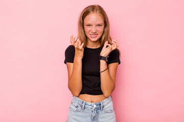 Caucasian teen girl isolated on pink background upset screaming with tense hands.