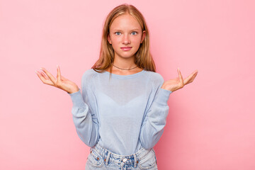 Caucasian teen girl isolated on pink background doubting and shrugging shoulders in questioning gesture.