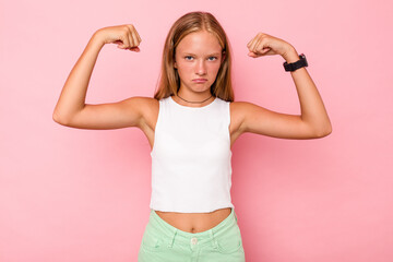 Caucasian teen girl isolated on pink background showing strength gesture with arms, symbol of...