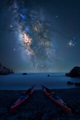 milky way over a beach with boats