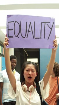 Vertical video. Asian girl holding a poster with the slogan: equality in a school. Feminism 