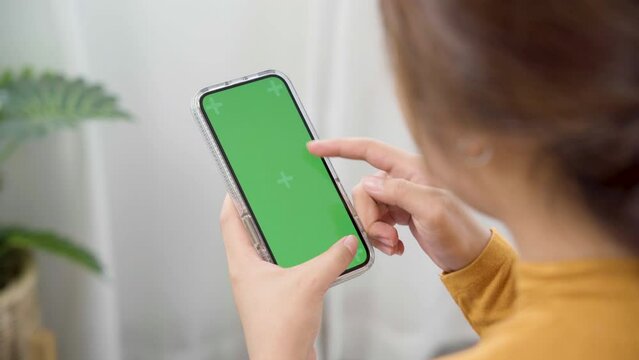 Woman using green screen for copy space closeup. mock-up on smartphone in hand, female sitting on bed holding mobile phone and touch screen while looking social.
