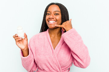Young African American woman wearing bathrobe holding a deodorant isolated on blue background showing a mobile phone call gesture with fingers.