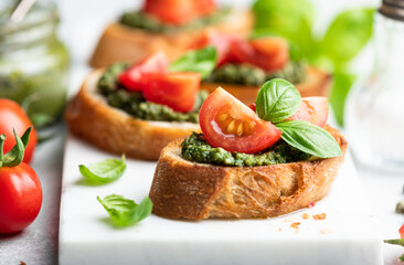 Pesto bruschetta with cherry tomatoes and basil, selective focus