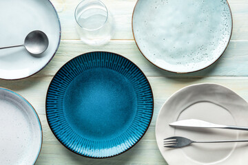 Modern tableware set with cutlery and a vibrant blue plate, with a glass, overhead flat lay shot....