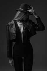 Obraz premium monochrome photo of teenage model adjusting fedora hat in studio.