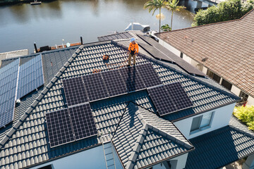 Solar panels and technician on luxury waterfront home
