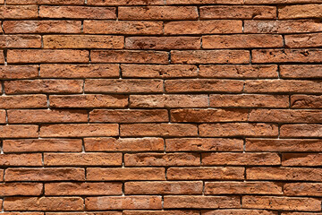 Red brick wall background. A wall of old, cracked bricks, with a weathered and faded surface. Restored brickwork of an old house.