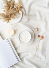 white blank book with cup of coffee and burning candle , cozy composition with opened book mockup