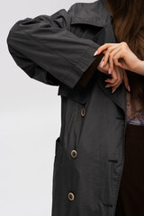 cropped view of model adjusting organic sleeve on trench coat isolated on grey.