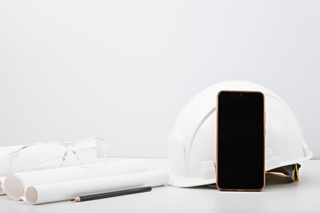 architect builder's desktop, helmet, project, black smartphone display, glasses. pencil on white...