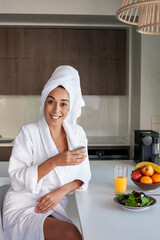 Lovely woman drinking morning coffee at home. Woman in bathrobe sitting in kitchen, looking at camera. Home, morning routine concept