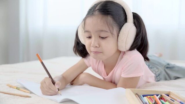 Cute primary school age girls drawing coloring picture with pencils on bed in holiday. Adorable child enjoying creative art hobby activity at home, children development at home concept. 
