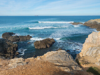 View of empty Praia Selvagem sand beach with ocean waves and sharp rock and cllifs at wild Rota Vicentina coast near Porto Covo, Portugal.