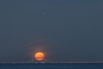 The connection of the full moon and Jupiter against the background of a cable-stayed bridge and the city 11.09.22.