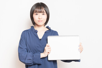 小さいスケッチブックを持っている若い女性